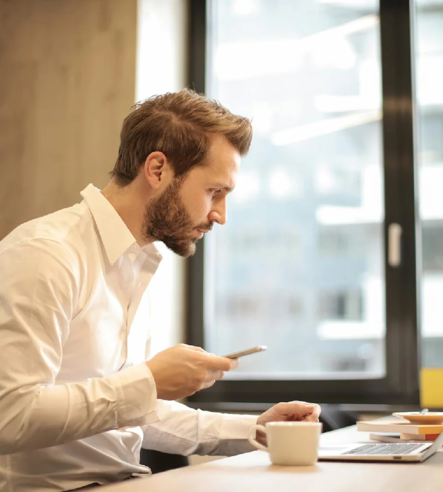 Executive reviewing information on mobile while working at desk